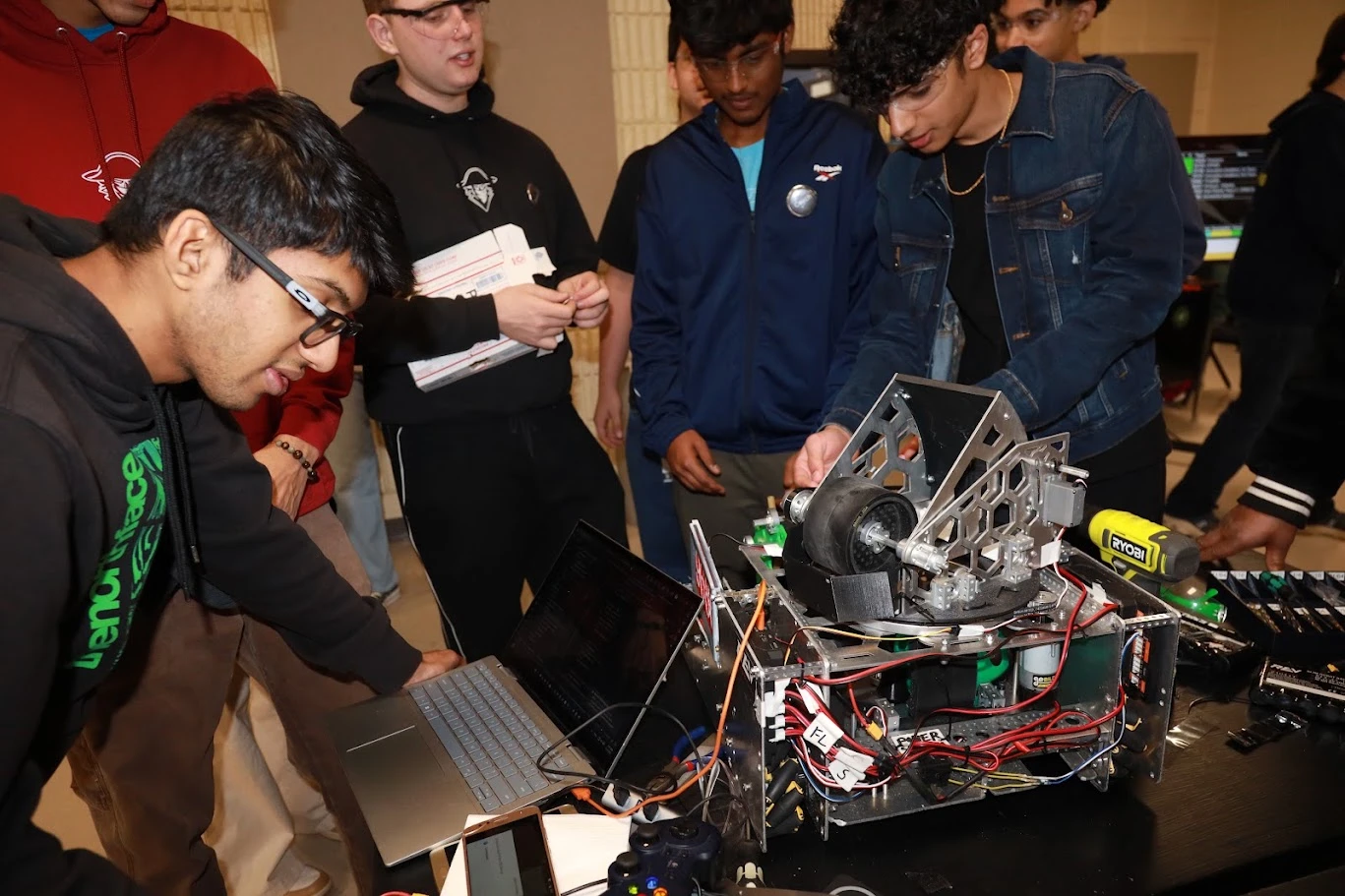 Team members gathered around the FTC robot and a laptop before a match