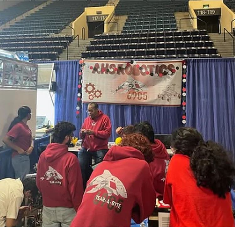 Coach and students at the AHS Robotics booth at an FRC event