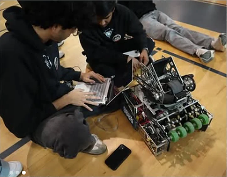 Students programming the FTC robot with a laptop on the gym floor