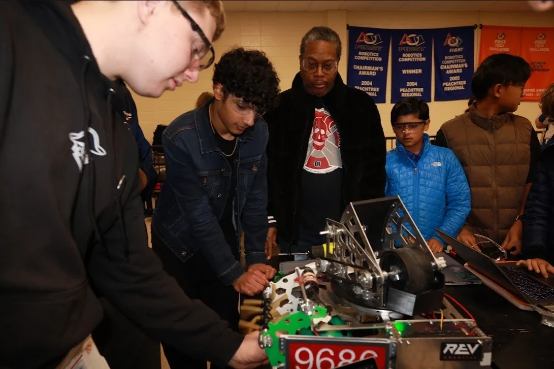 Coach and students looking over the FTC robot at an outreach event