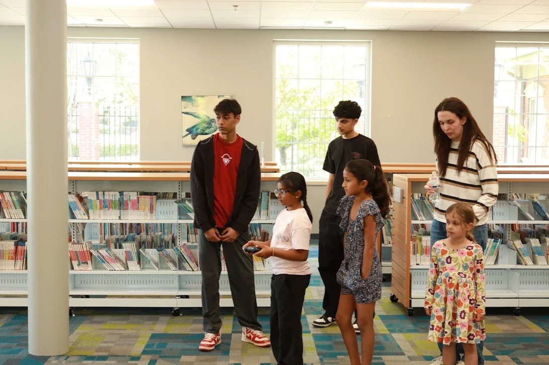 Club members showing a robot to kids at a library outreach event