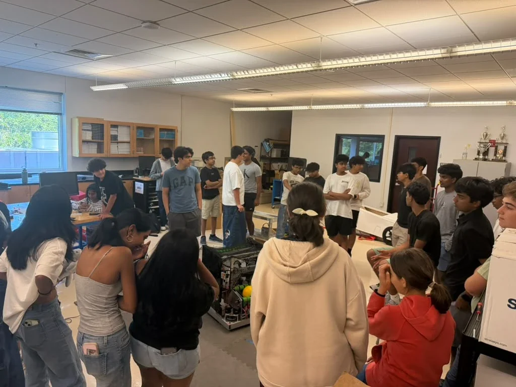 Students and new members gathered around the robot in the robotics lab