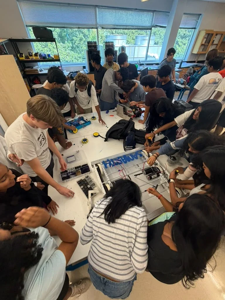 Club members crowded around a build table assembling a robot chassis