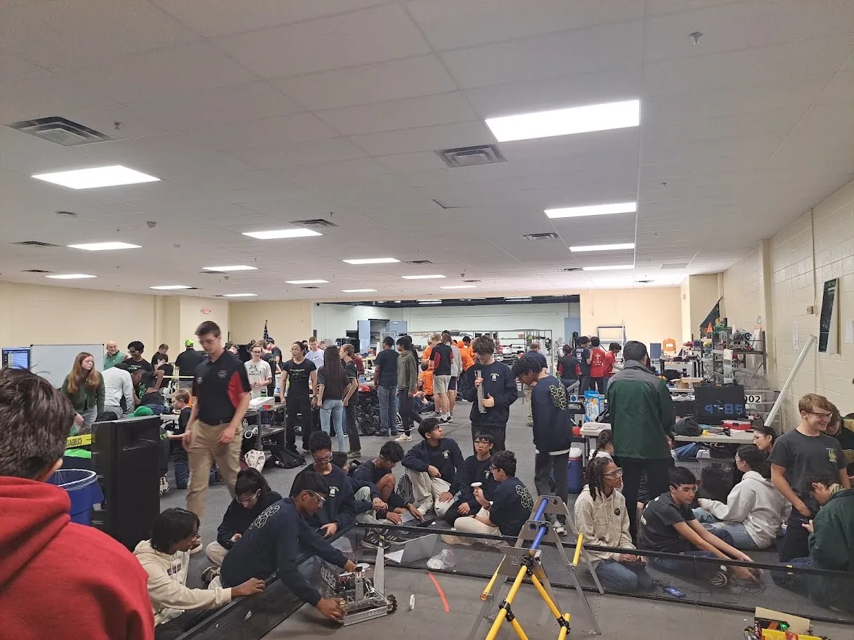 Students and mentors gathered around a practice field at a robotics event