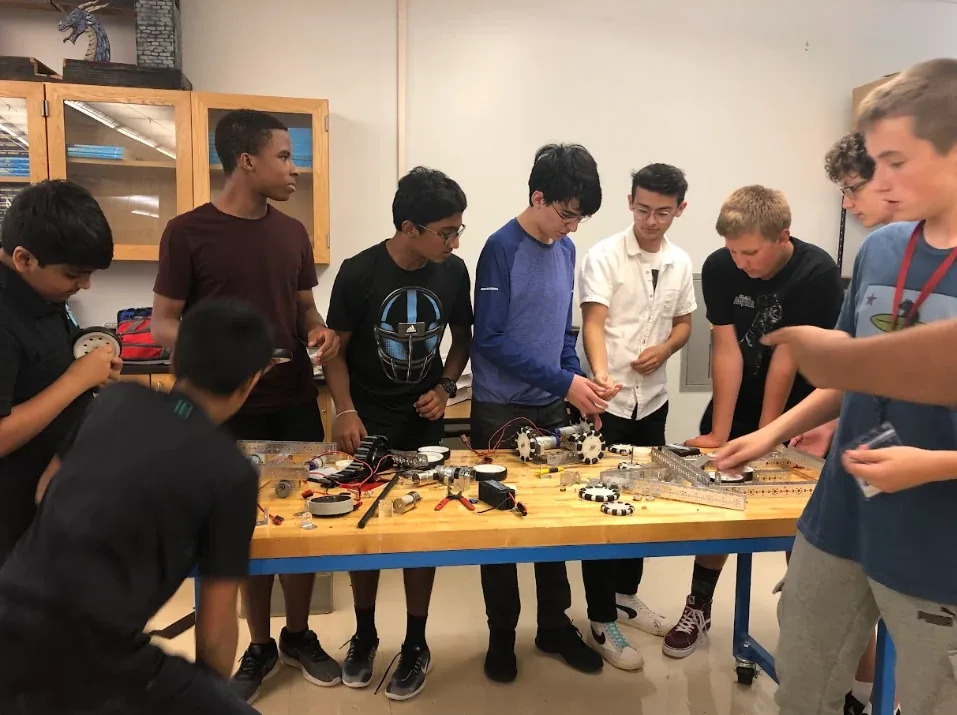 A group of students gathered around a build table at a workshop
